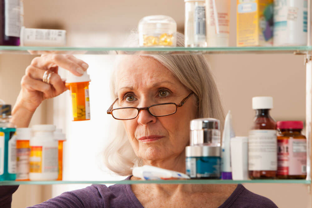 Woman looking at medications in medicine cabinet